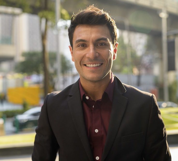 Face of happy young handsome Hispanic businessman smiling in the city